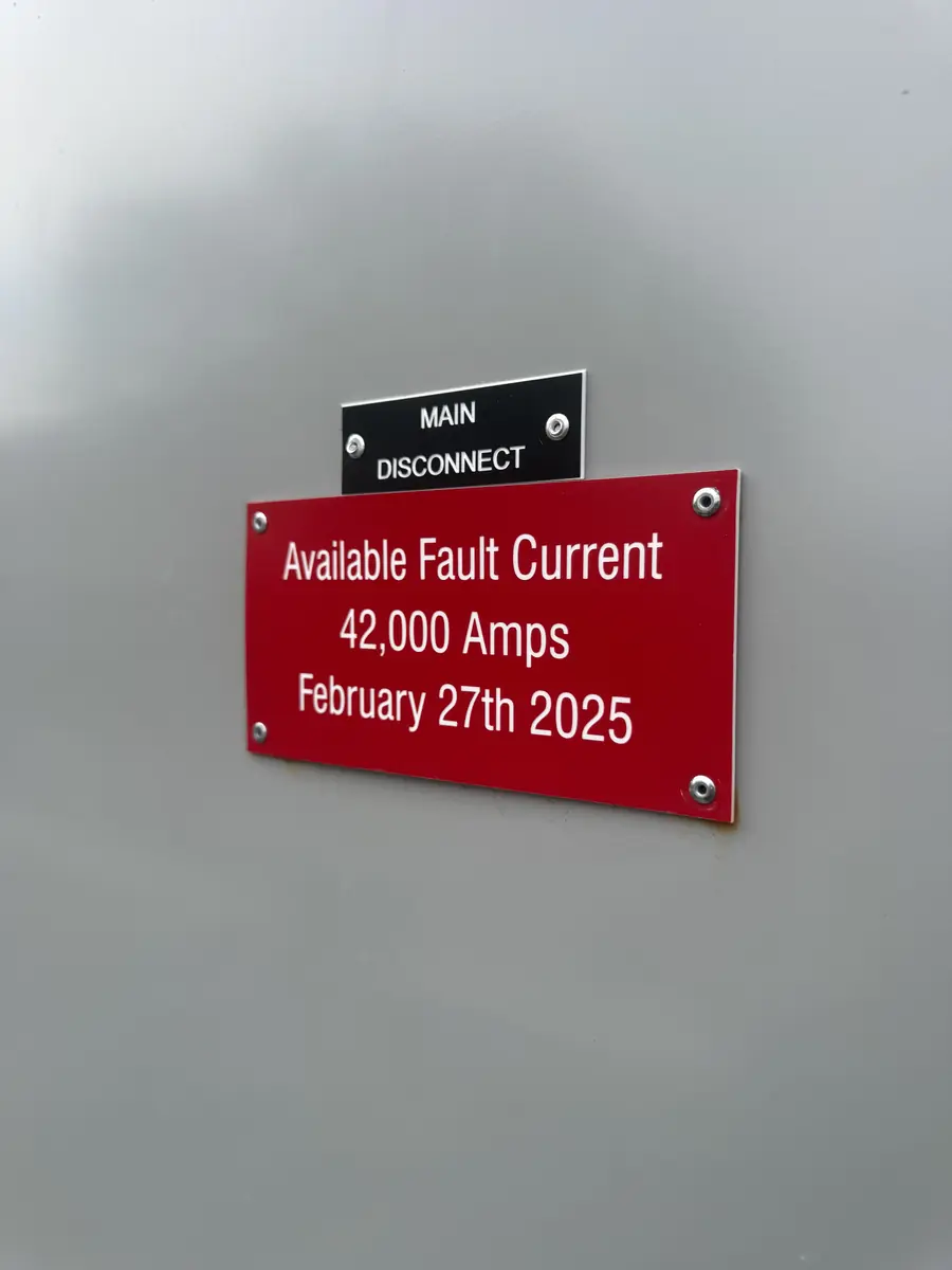 Laser-engraved MAIN DISCONNECT and red fault-current phenolic labels screwed to a switchgear door